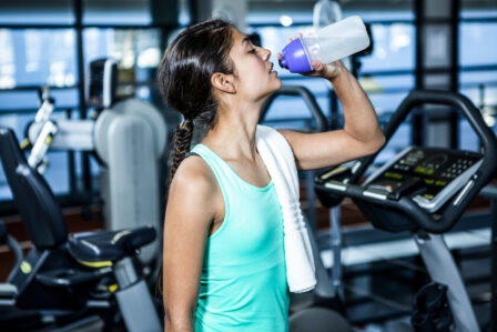 kobieta pijąca napój energetyczny na siłowni